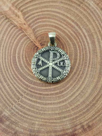 Фото кулона хризма  монограмма Христа из бронзы на предметном фоне.