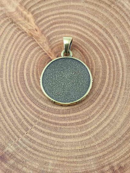 Фотография кулона хризма  монограмма Христа из бронзы на предметном фоне с обратной стороны.