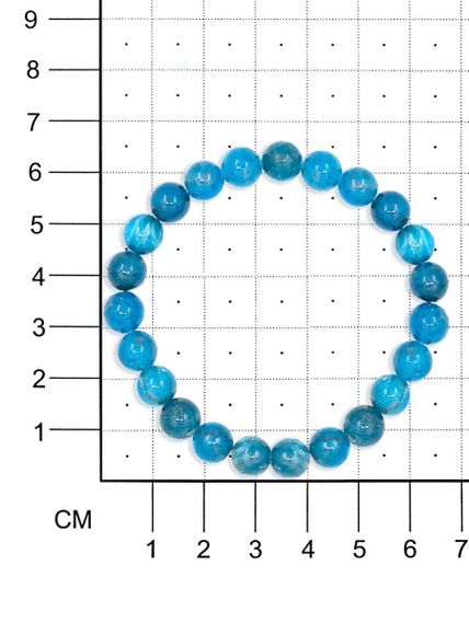 Фото браслета из бусин апатита на белом фоне на размерной сетке