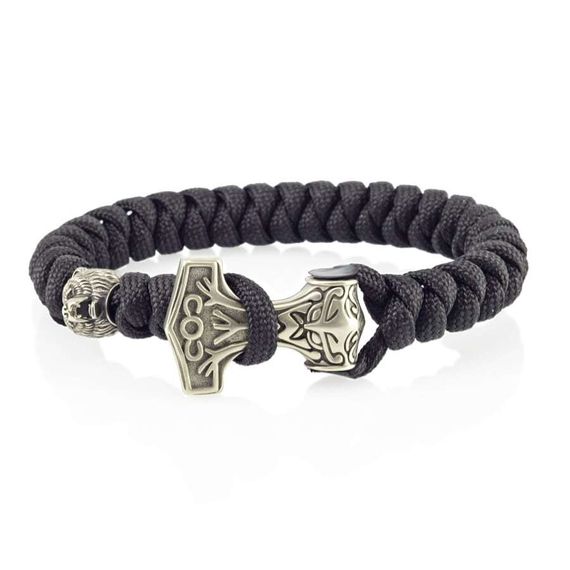 Фотография браслета из паракорда с шармами молот Тора и медведь на столе.